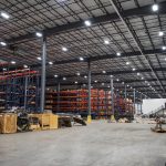 Interior of a spacious warehouse with tall shelving units and industrial materials, example of how Long Bay Systems works.